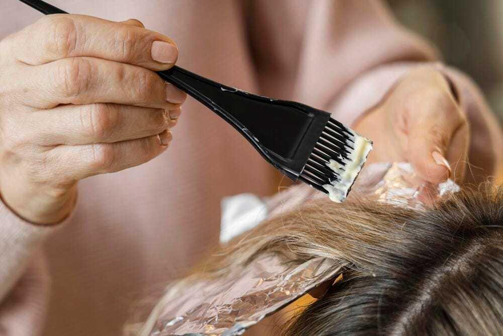 Hair coloring process with a brush applying dye to hair over foil.